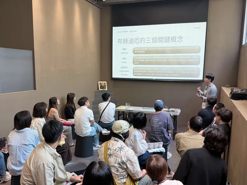 閱讀聚會的導讀時間，主持人在投影幕前分享書中的關鍵概念，大家坐著聆聽